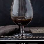 A pinterest pin showing a spanish carajillo in a brandy glass on a cutting board.