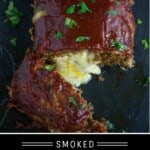 Smoked and stuffed meatloaf on a platter with a slice showing cheese oozing out.