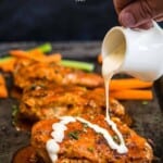 pinterest pin showing grilled stuffed Buffalo chicken wings on a sheet tray and drizzled in ranch.