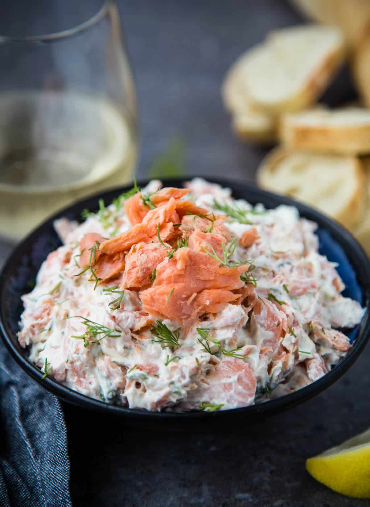 Smoked Salmon Dip in a serving bowl with a glass of white wine and baguette slices