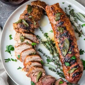 Grilled Pork Tenderloin on a platter topped with fried sage butter sauce