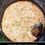 A grilled Shepherd's Pie with browned mashed potatoes and a spoon that has removed a small portion from the pie showing the minced meat filling.