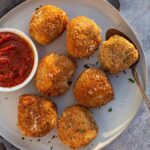 Arancini balls on a plate with a side of marinara.