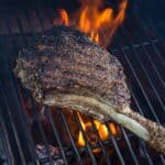 Tomahawk steak cooking over direct heat on a Big Green Egg.