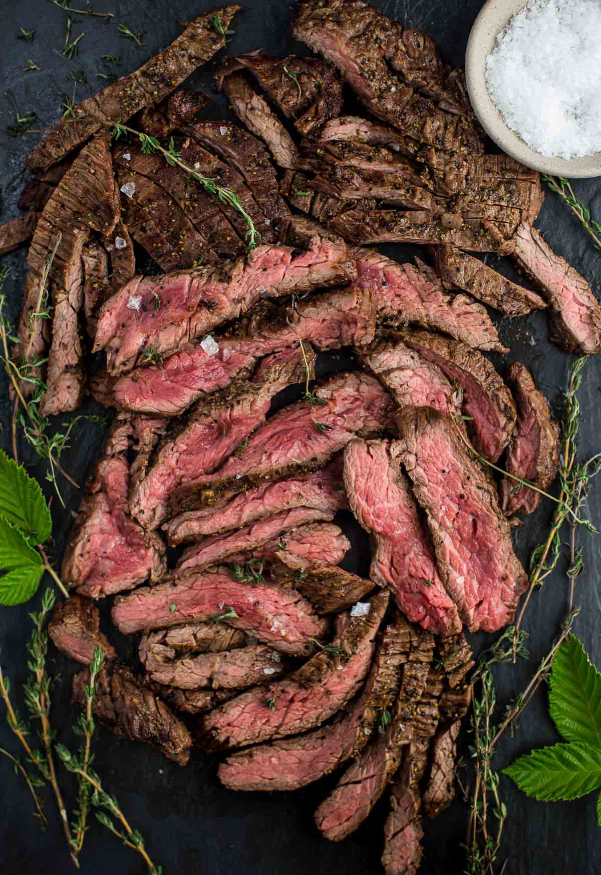 A medium rare steak cut into slices on a serving platter