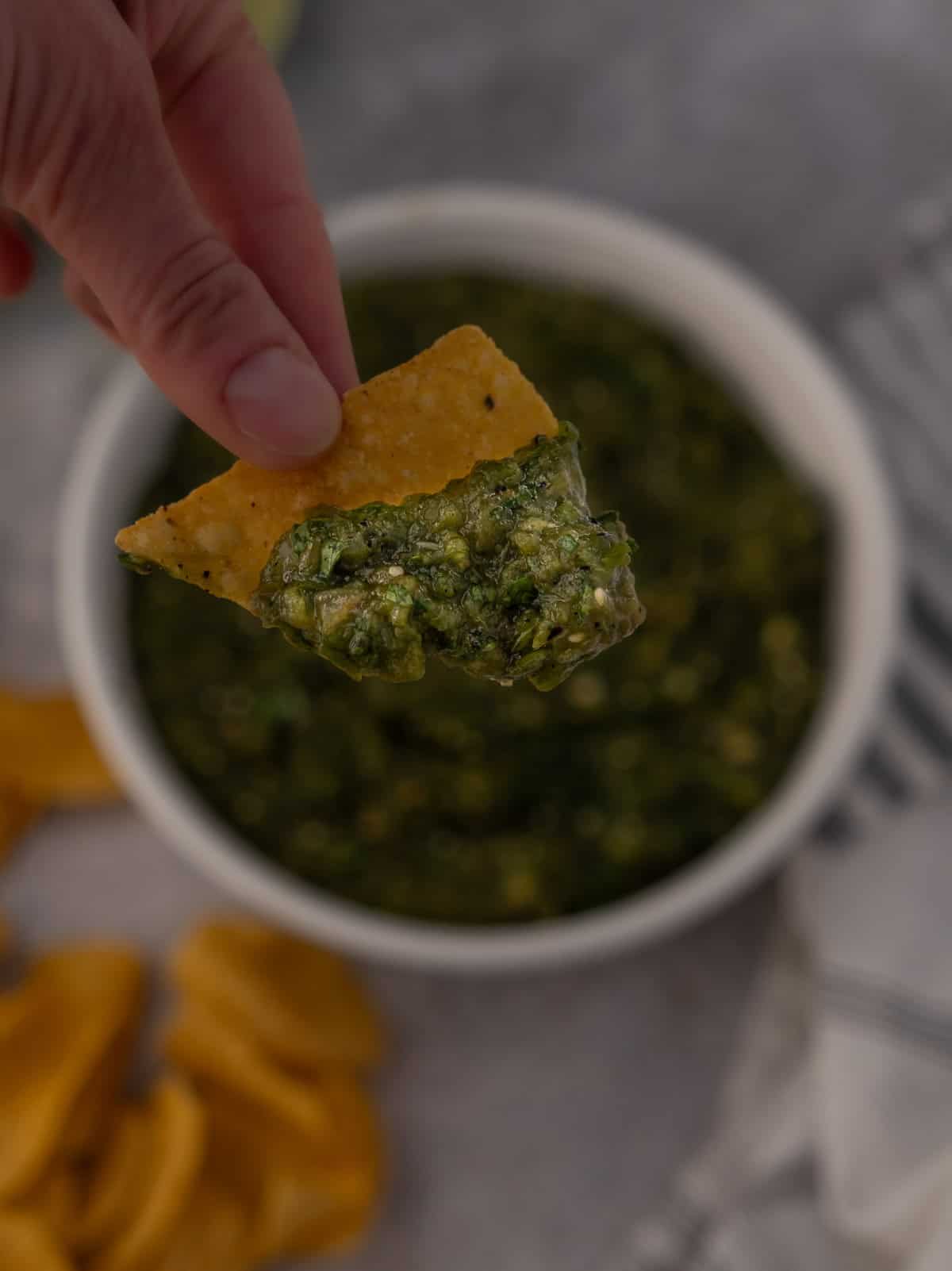 A chip being dipped into a Hatch green chile salsa.