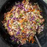 Mayo and Mustard coleslaw in a dark bowl with a spoon.