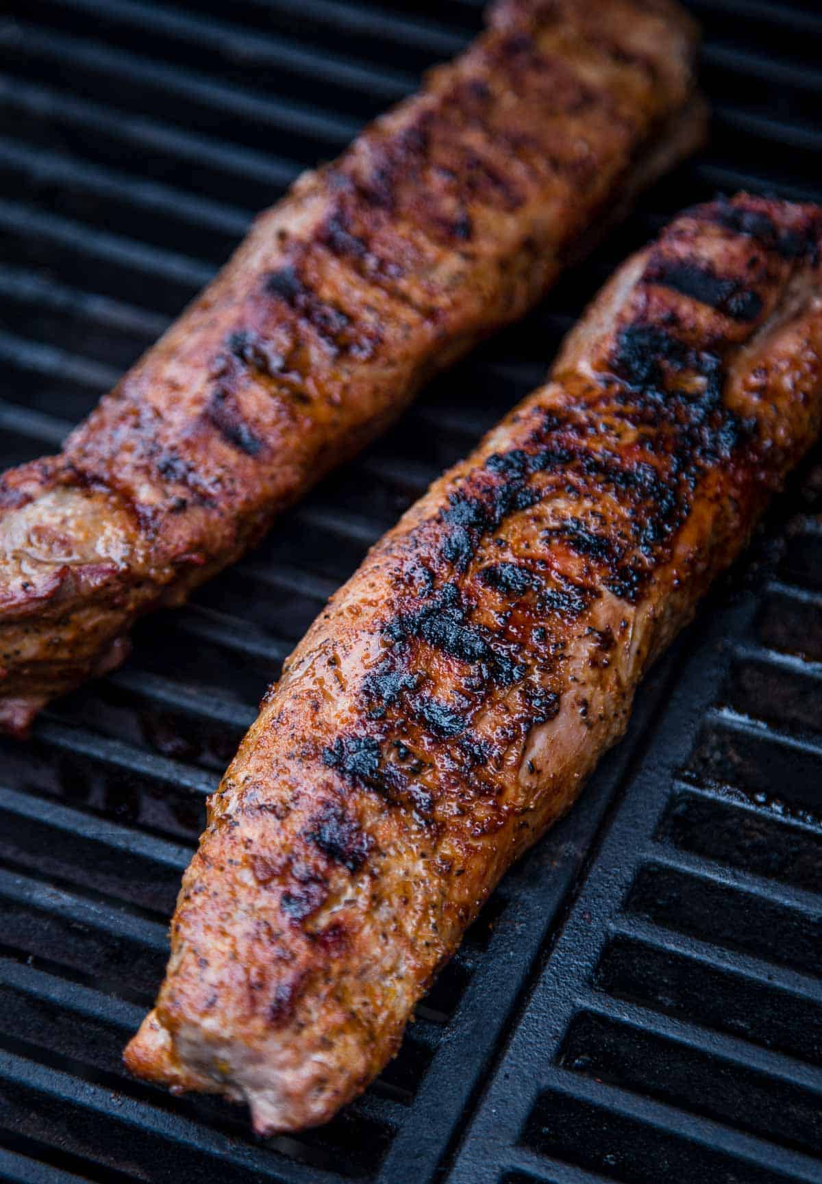 Two grilled pork tenderloins on a hot grill