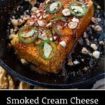 Pin showing smoked cream cheese in cast iron pan with jalapeno topping, hot honey, and crushed hazelnuts.