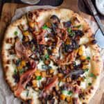 Butternut Squash pizza with caramelized onions and sage on a cutting board.