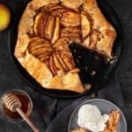 A grilled apple galette on a serving platter with a slice removed and on a plate topped with ice cream.