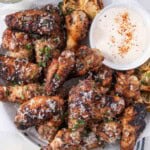 Garlic Parmesan wings with dipping sauce on a plate with lemon.