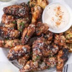 Grilled garlic parmesan wings on a plate with ranch dipping sauce.