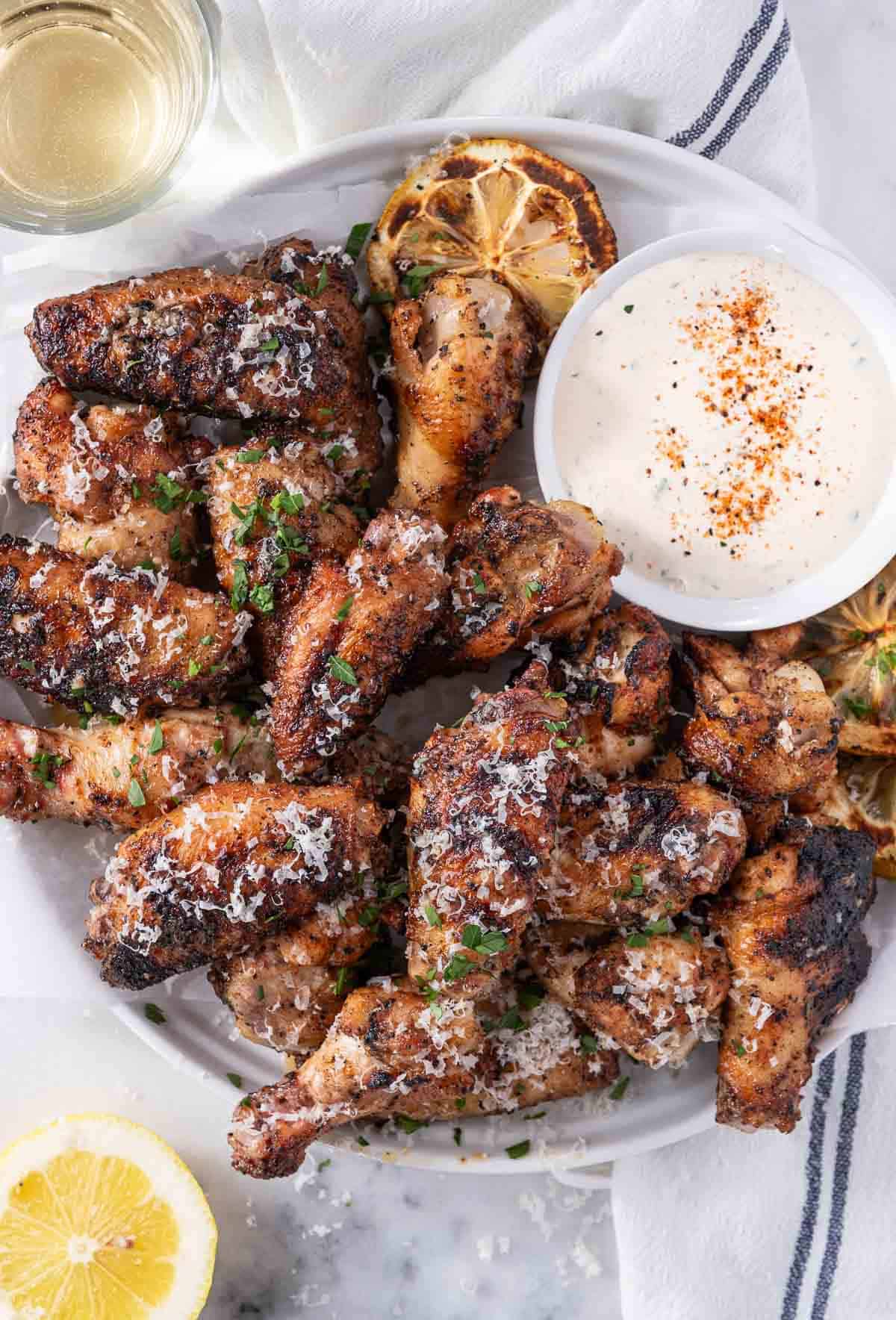 Garlic Parmesan wings with dipping sauce on a plate with lemon.