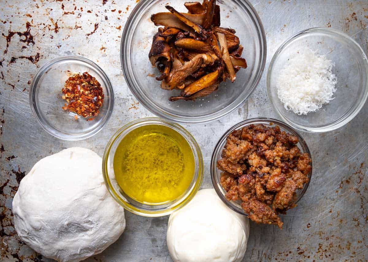 Ingredients for sausage and chanterelle mushroom pizza on a sheet pan