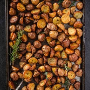 Perfect Roasted Potatoes on a sheetpan with a sprig of rosemary