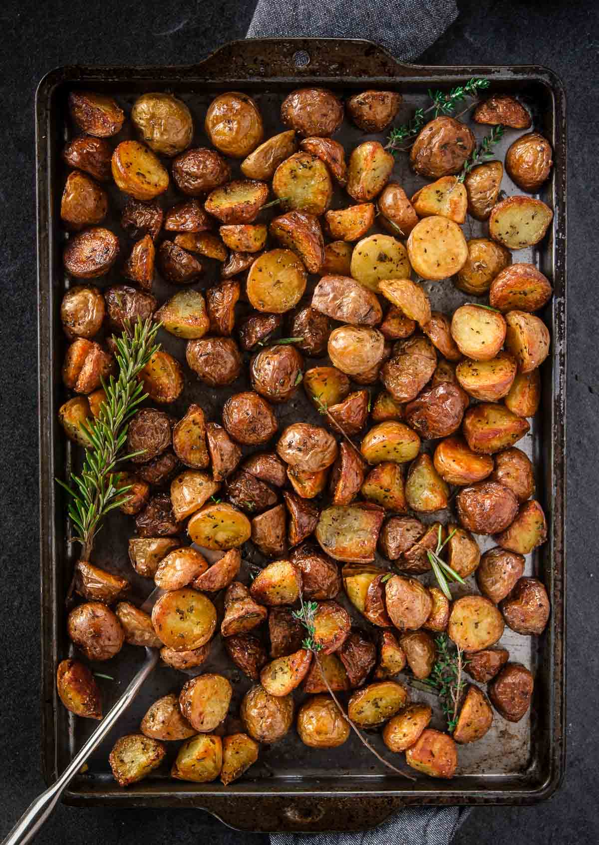 Perfect Roasted Potatoes on a sheet pan with a sprig of rosemary