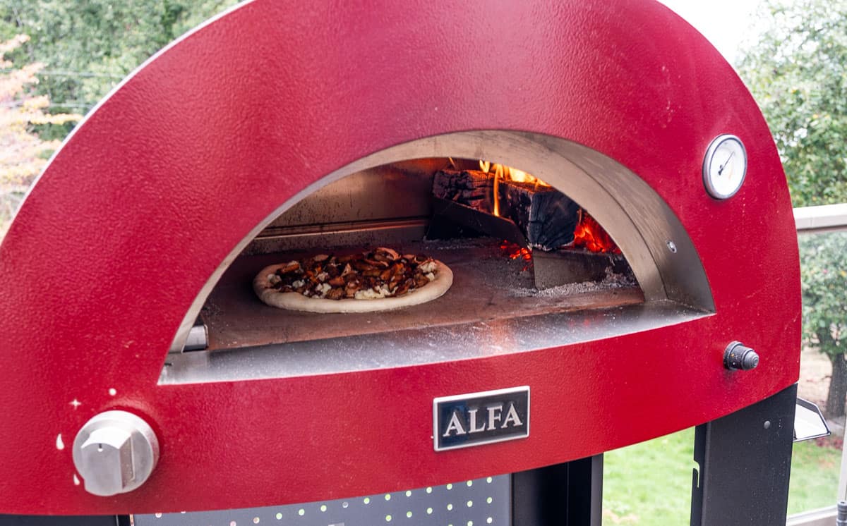 A pizza cooking in an Alfa Forni pizze 2 outdoor pizza oven