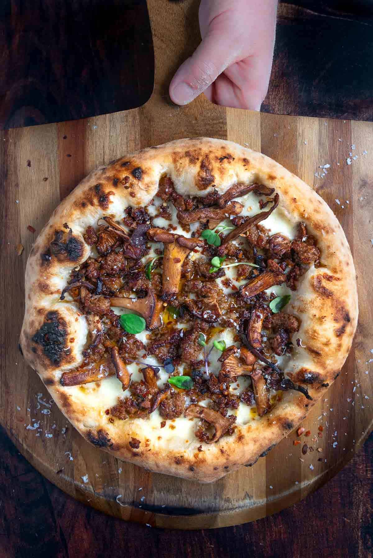 Sausage and Chanterelle Mushroom Pizza on a cutting board