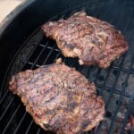 Two ribeye steaks on the grill over direct heat.