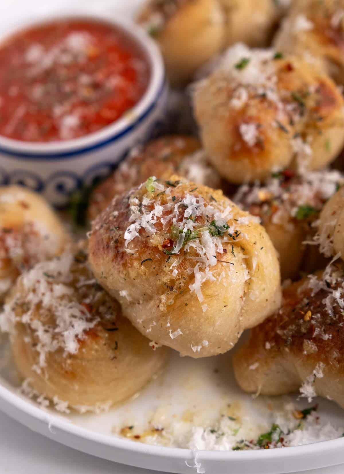 A garlic knot topped with parmesan cheese on a serving platter