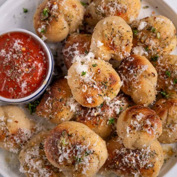 Homemade garlic knots on a platter with marinara sauce