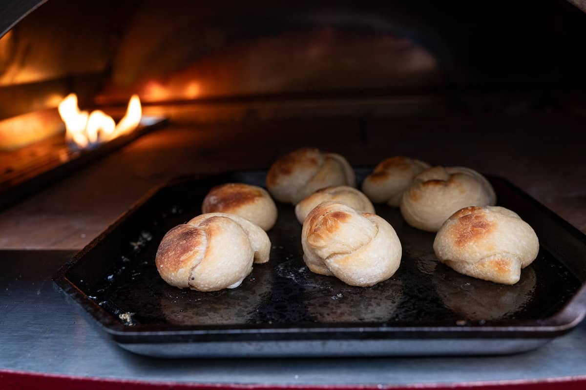 Garlic knots on a cast iron pan inside a pizza oven