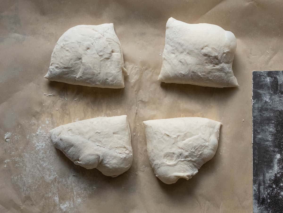 pizza dough cut into quarters on a baking sheet