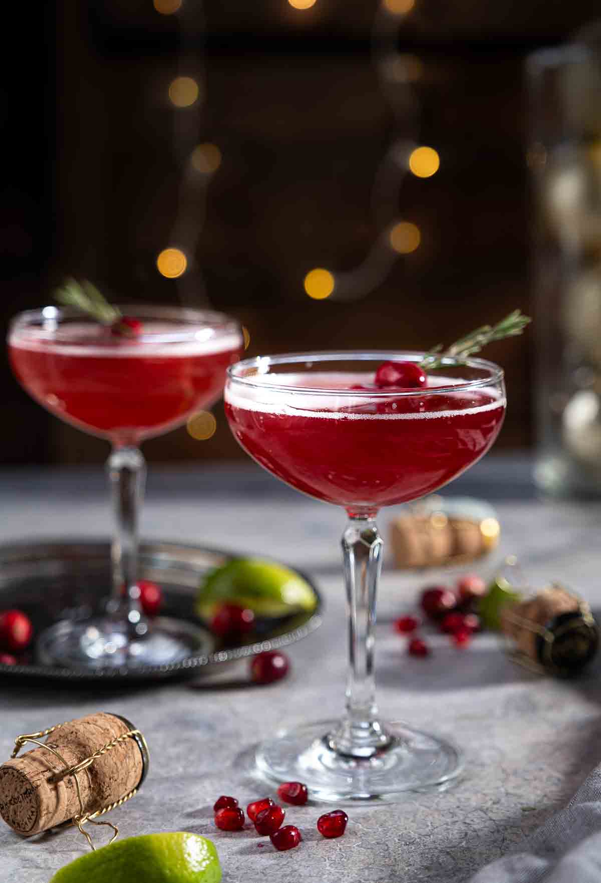 Two Christmas Mimosas on a table garnished with pomegranate and cranberries