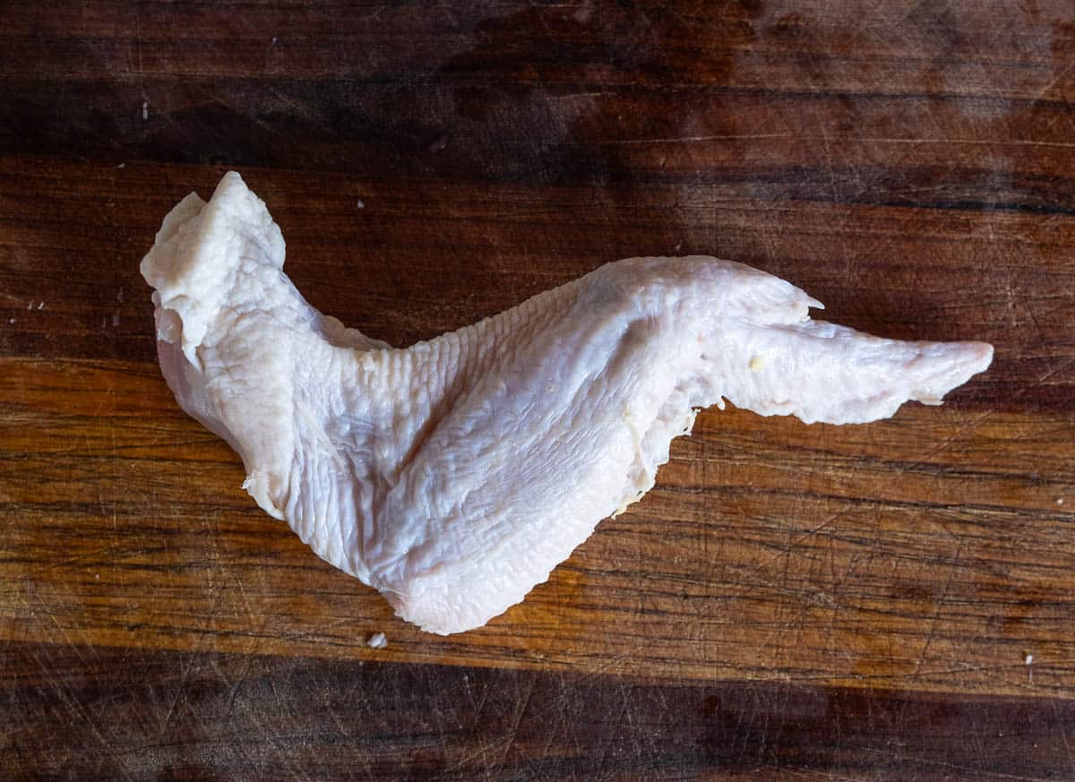 The front side of a whole chicken wing, not yet separated into the drum, flat, and winglet.