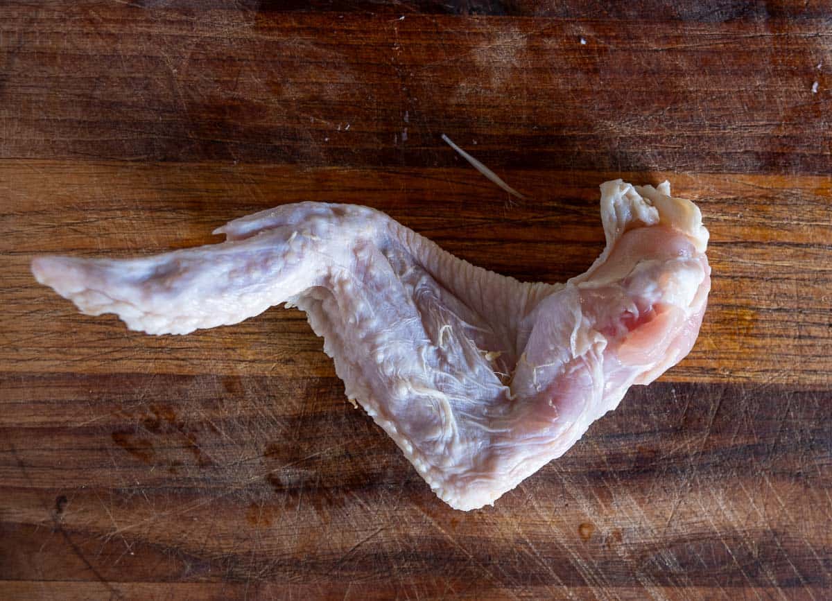 The back side of a whole chicken wing, not yet separated into the drum, flat, and winglet.