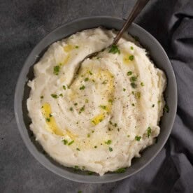 Horseradish mashed potatoes in a bowl with melted butter and chives.