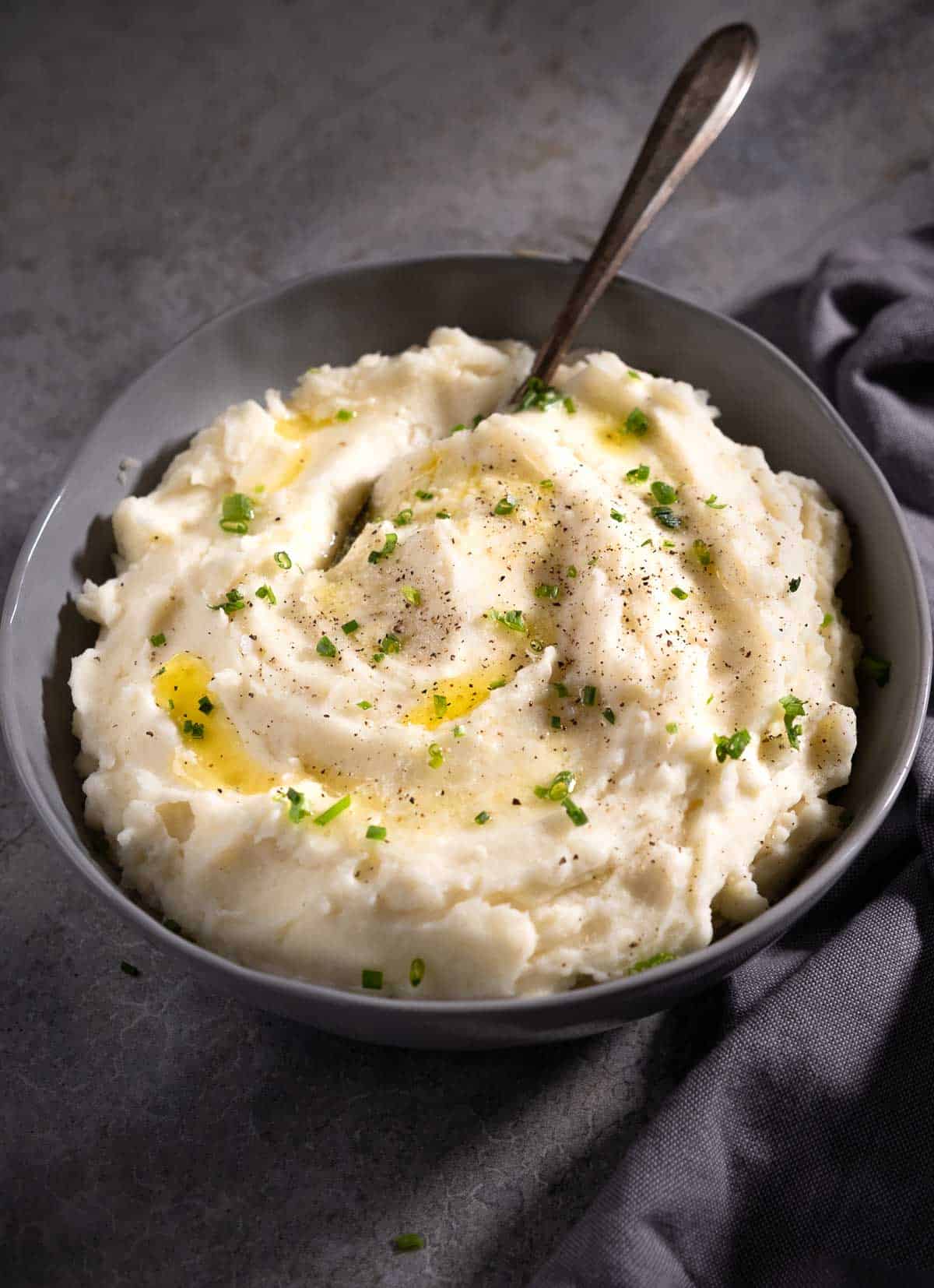 Horseradish mashed potatoes in a bowl topped with melted butter and chives.