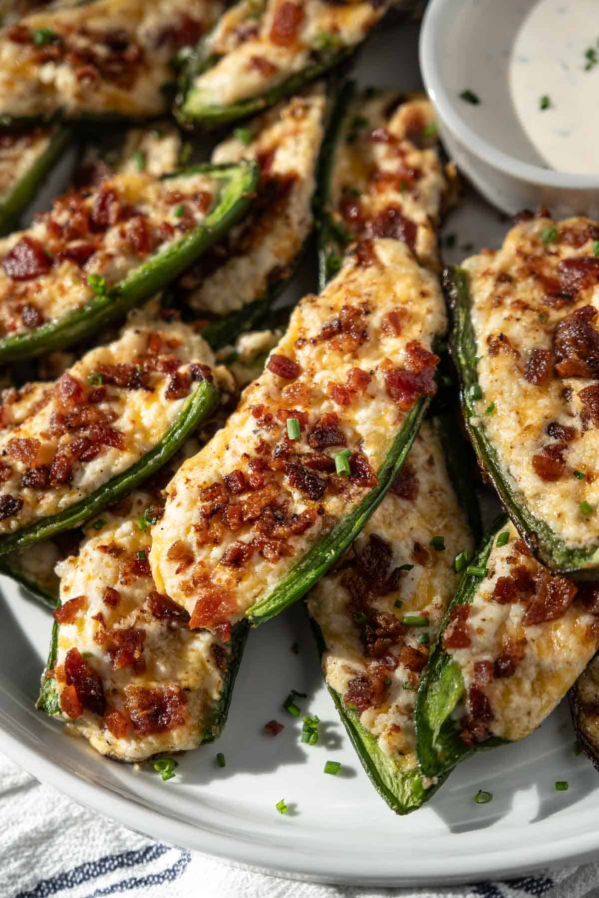 A cheesy jalapeño popper topped with crispy grilled bacon on a serving platter. 