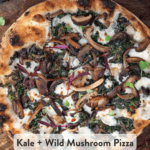 A pinterest pin showing an uncut kale pizza topped with mushrooms, crispy kale, cheese, and red pepper flakes on a wooden cutting board.