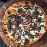 A kale pizza with wild mushrooms, cheese, and red chile flakes.