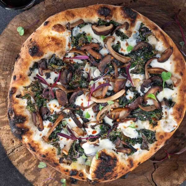 A kale pizza with wild mushrooms, cheese, and red chile flakes.