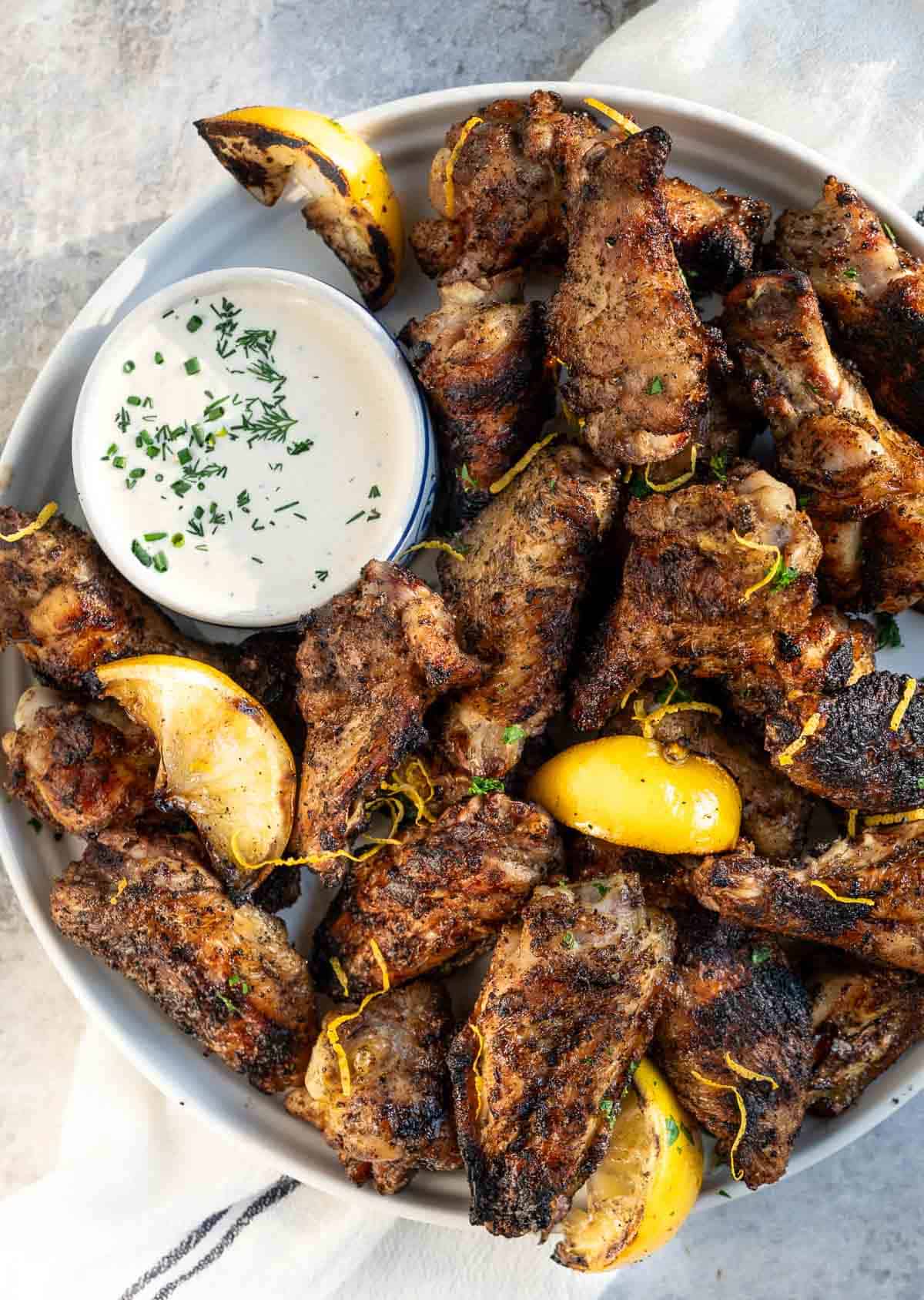 Lemon pepper chicken wings on a white plate and a side of ranch.