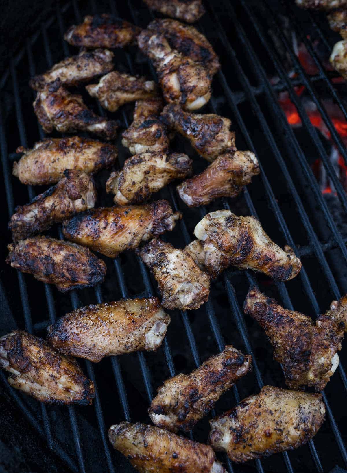 Chicken wings cooking on a grill.