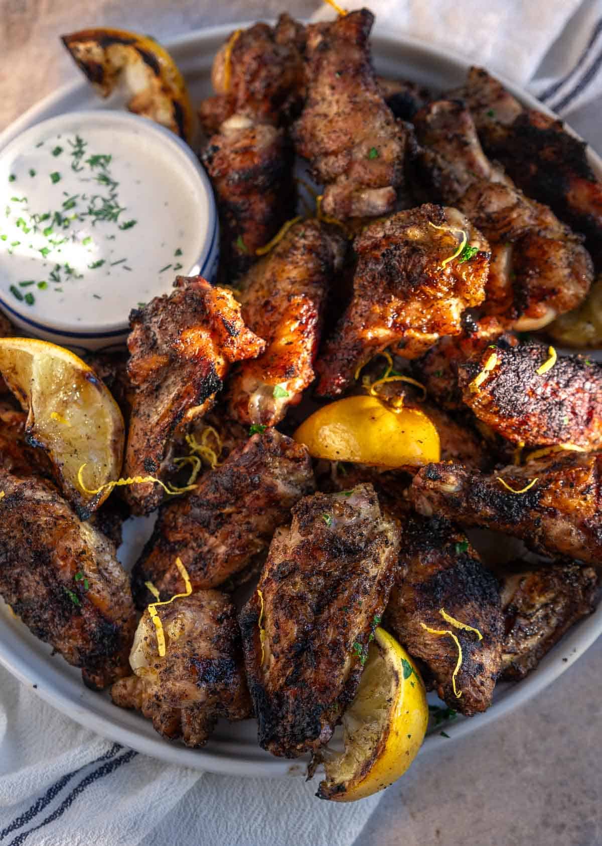 Grilled Lemon Pepper Chicken Wings on a white plate with a bowl of homemade ranch dressing.