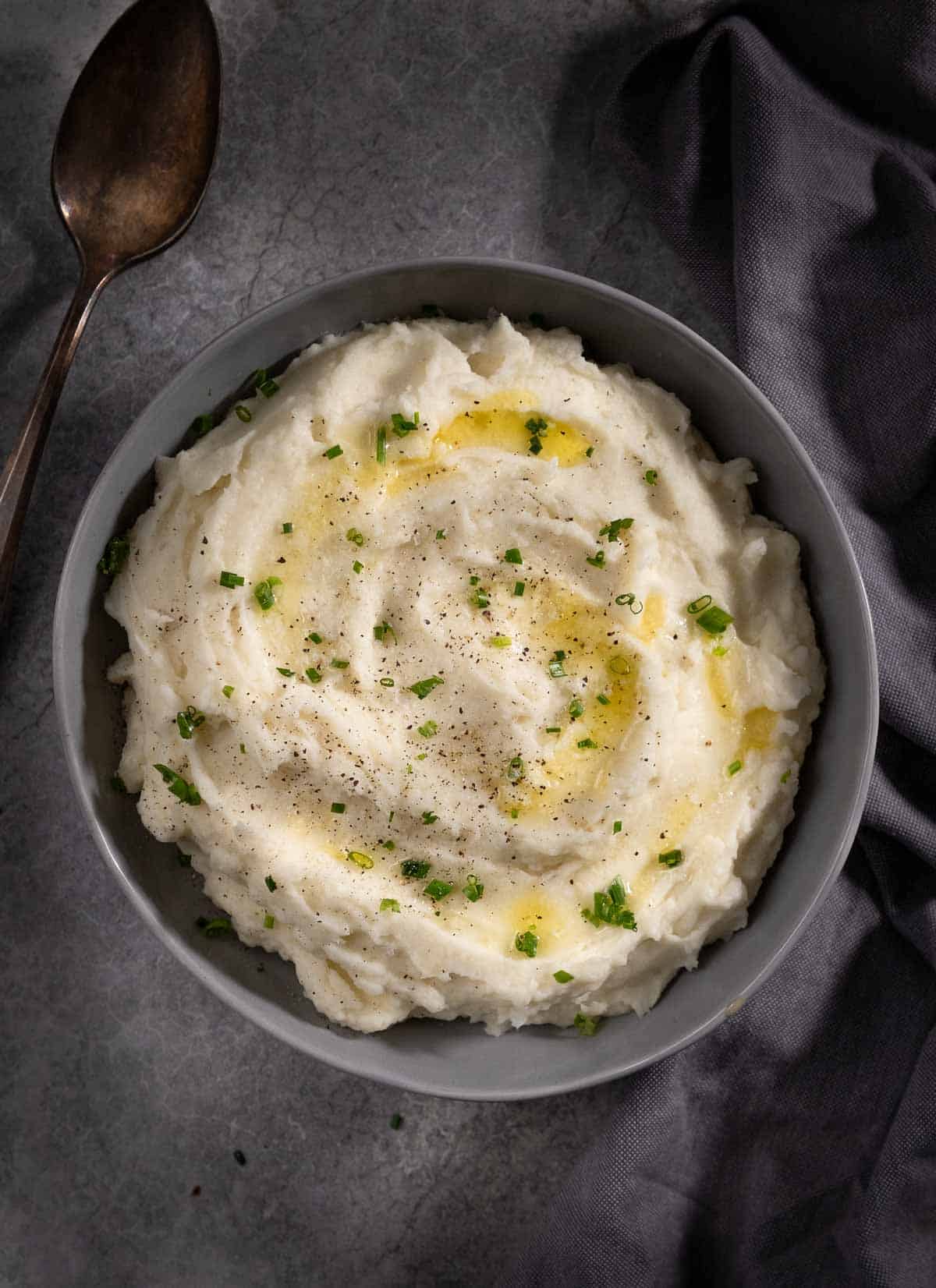 Horseradish Mashed Potatoes in a bowl topped with melted butter and chives.