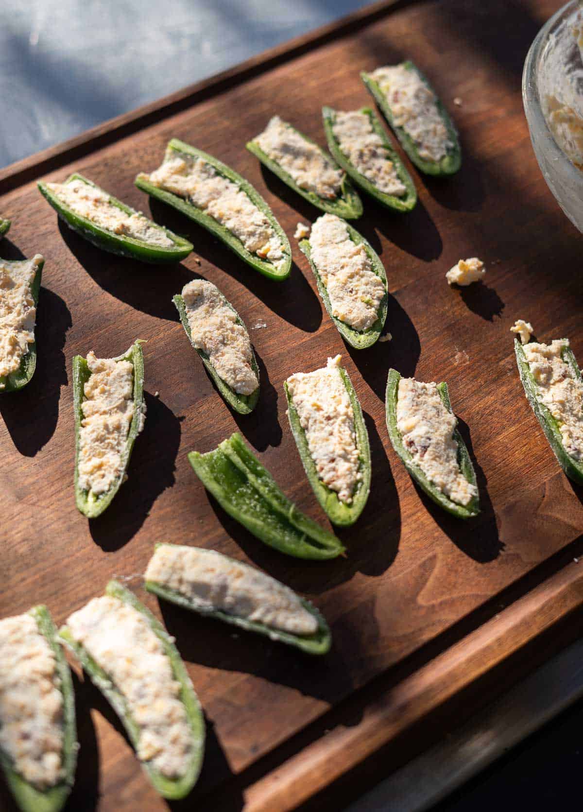 stuffed Grilled jalapeño poppers on a cutting board ready for the grill.