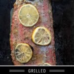 A grilled salmon filet covered in lemons with a garlic lemon paste glaze.