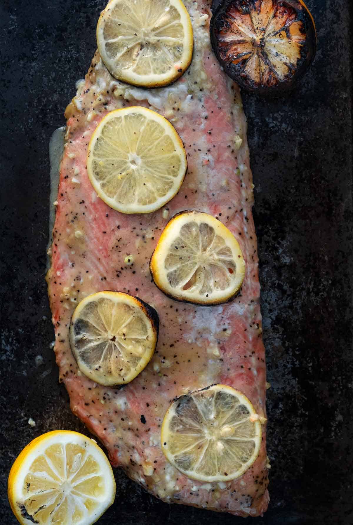 Grilled Lemon Garlic Salmon on a sheet pan topped with grilled lemon slices. 