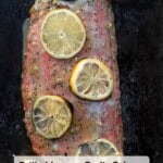 A grilled salmon filet covered in lemons with a garlic lemon paste glaze.