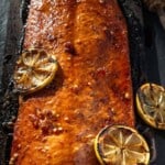 Pinterest pin showing a salmon on a cedar plank over direct heat glazed with hot honey.