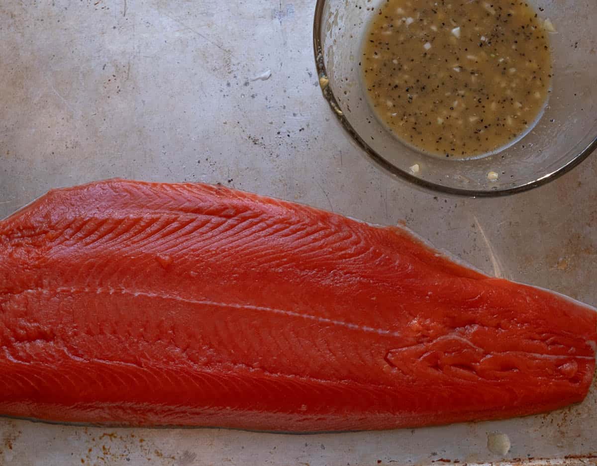 Raw salmon filet with lemon garlic honey paste in a bowl. 